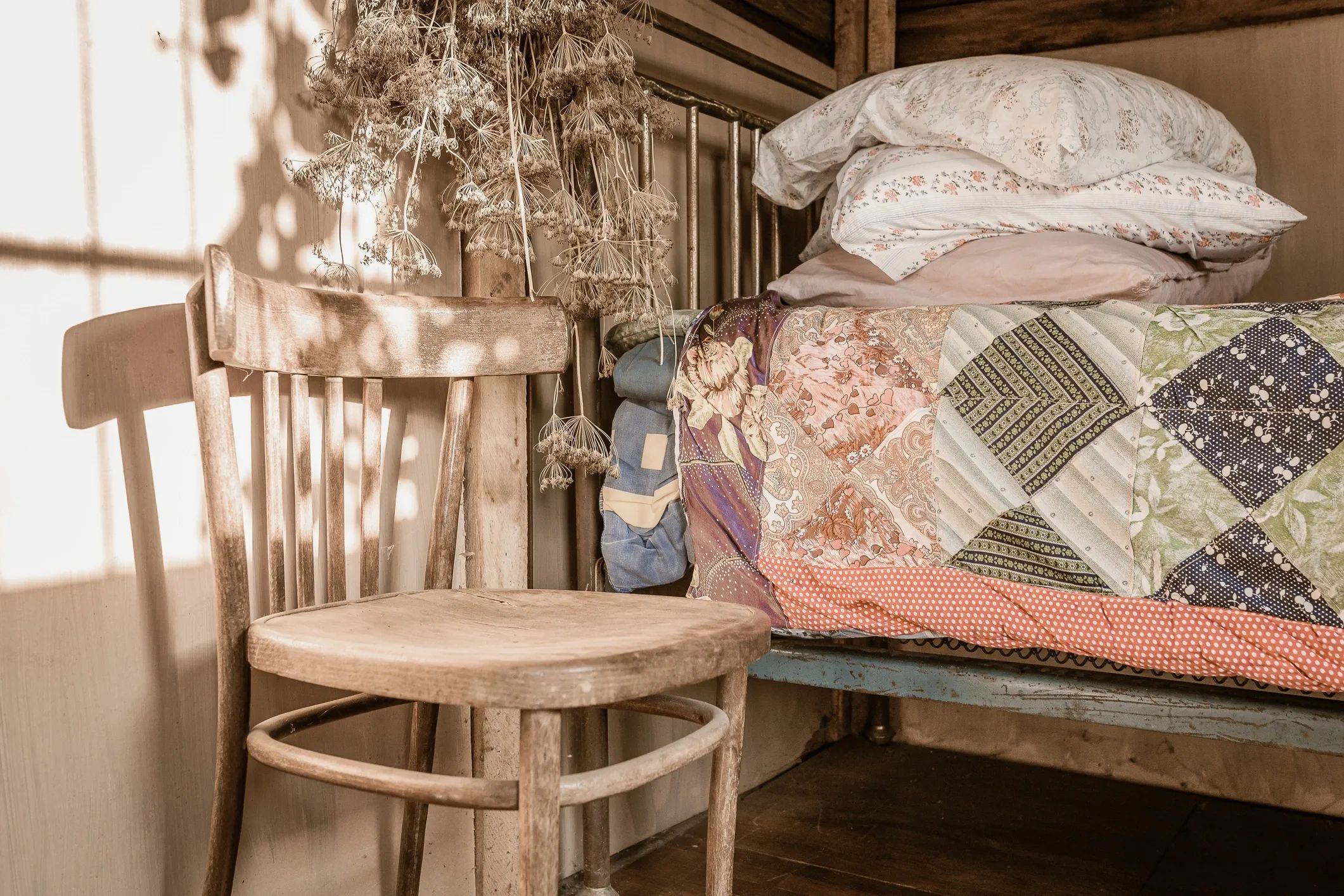 Rustic wooden chair with patchwork quilts in cottage interior